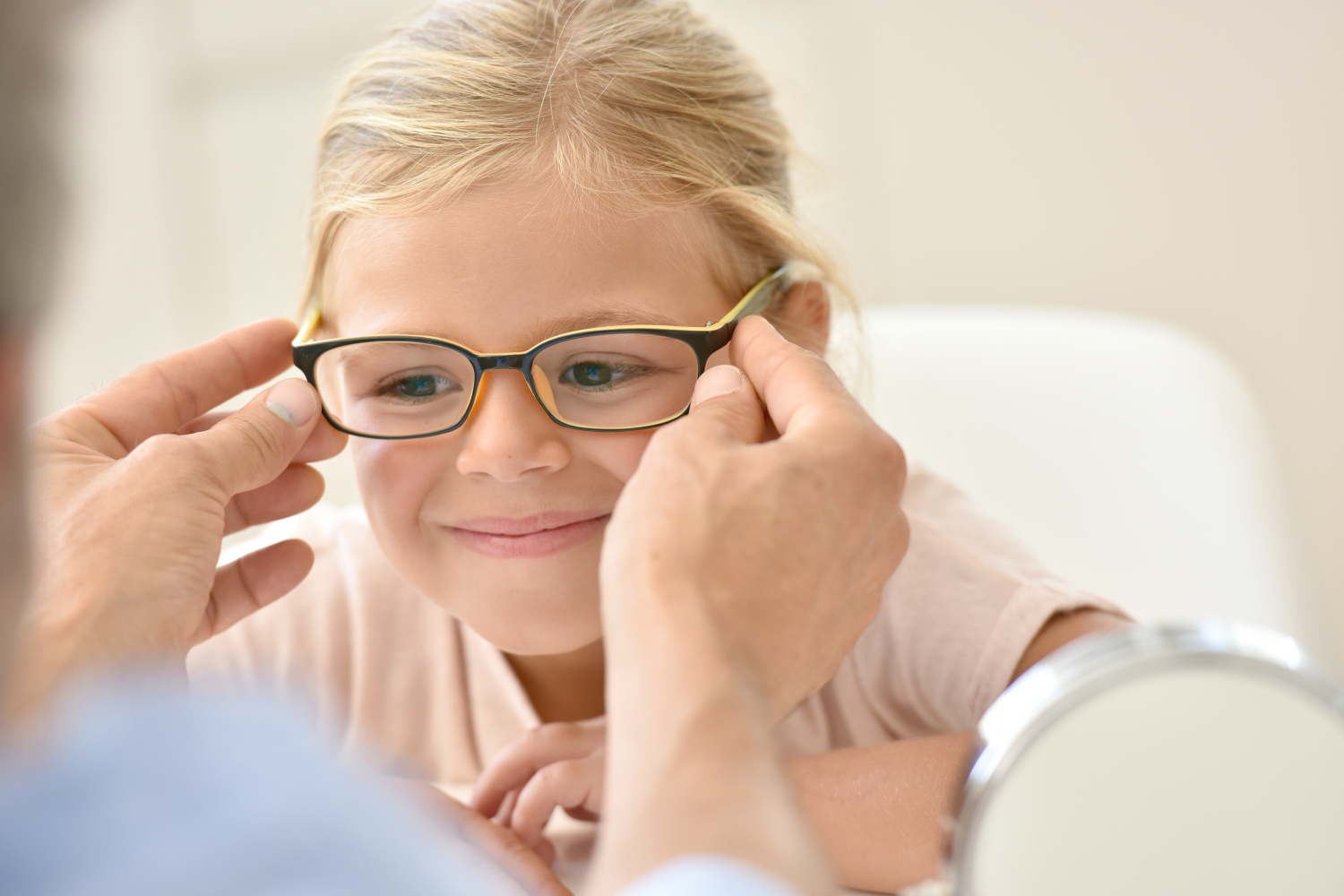 young blonde girl trying on pair of glasses