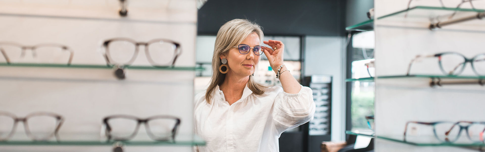 Reflection of blonde woman trying on glasses