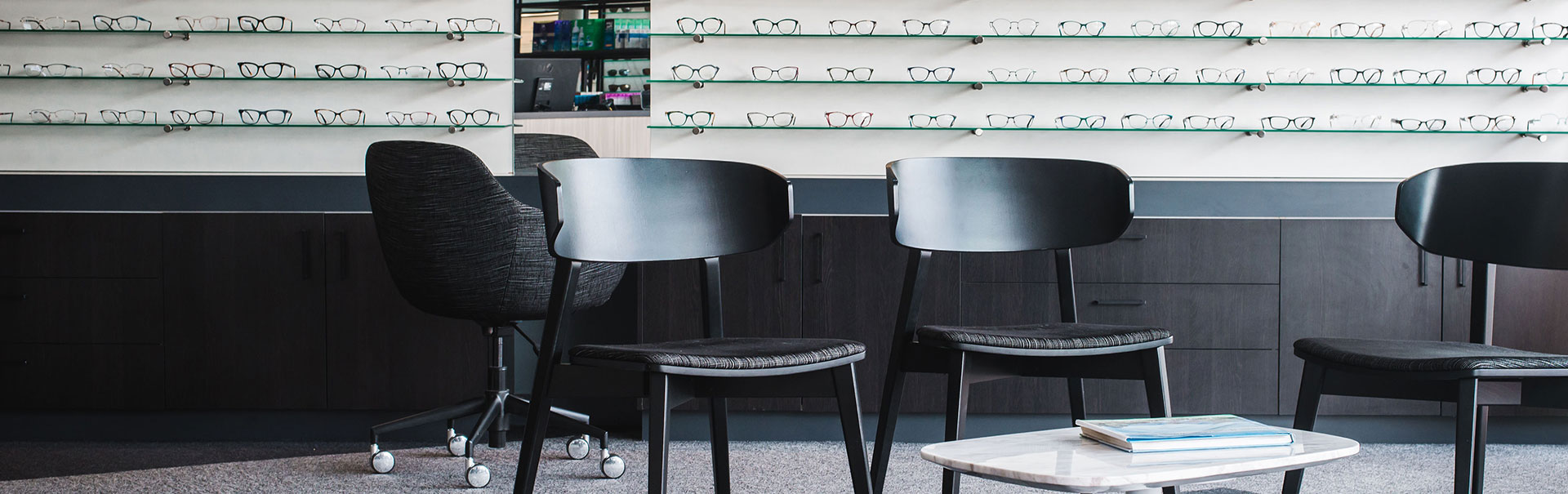Sitting area with wall shelves of eyeglasses in the background